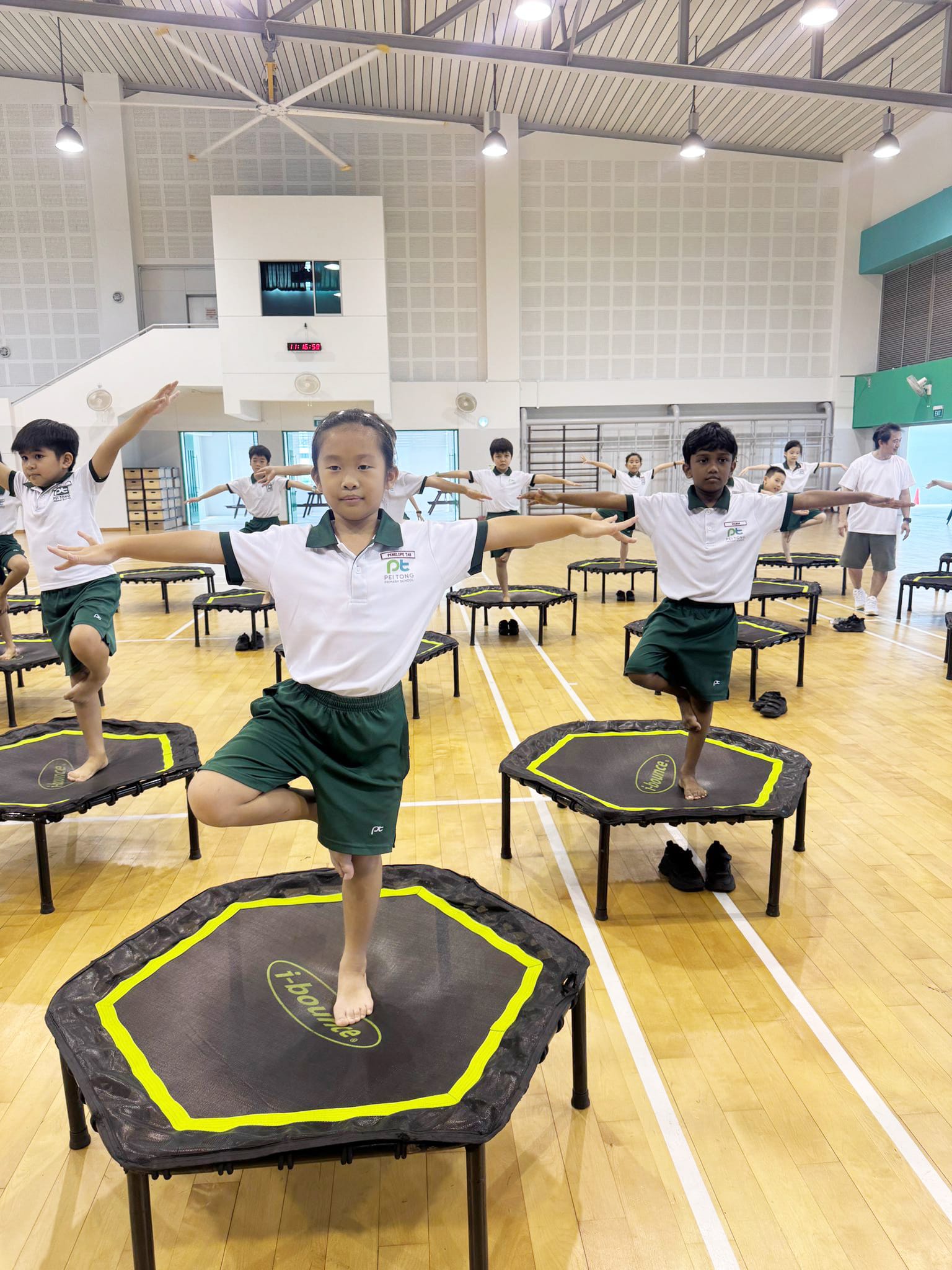 Primary 1 and Primary 2 students balance on mini trampolines during an iBounce lesson, improving balance, coordination, core strength, and body control through engaging movement activities.